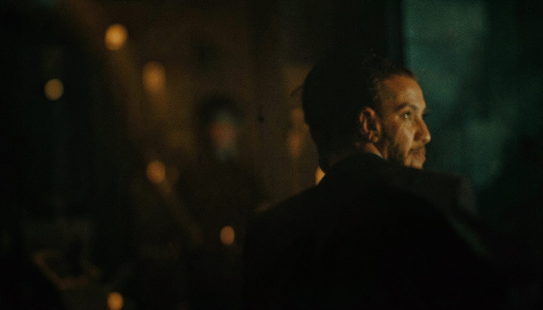 A dimly lit cinematic scene with soft amber and teal tones, evoking a contemplative film atmosphere.